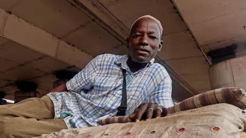 Monday Idara/BBC Liya’u Sa’adu lying on his mattress under a bridge in Lagos, Nigeria