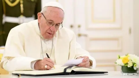 Getty Images Pope Francis signing a document