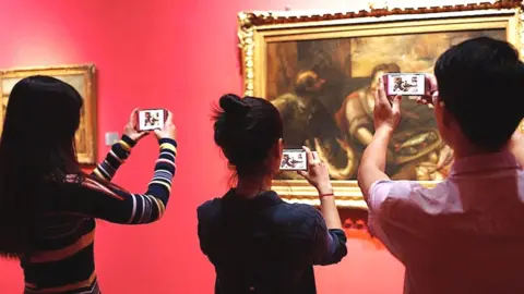 Artivive People looking at a painting through smartphone AR app