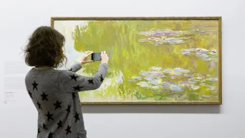 Artivive Woman looking at Money water lilies painting through AR app
